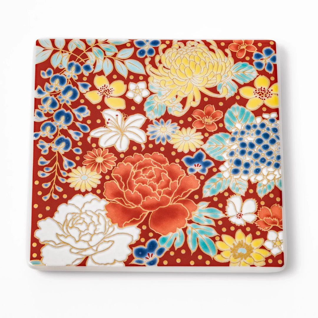 Square Japanese ceramic coaster with vivid red base featuring peony, chrysanthemum, and floral motifs in multicolor design.