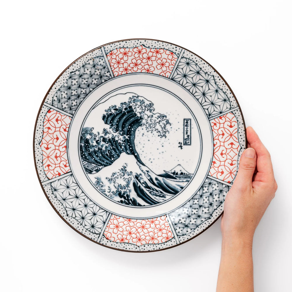 Japanese porcelain dinner plate featuring Hokusai Great Wave design with red and blue geometric border patterns.