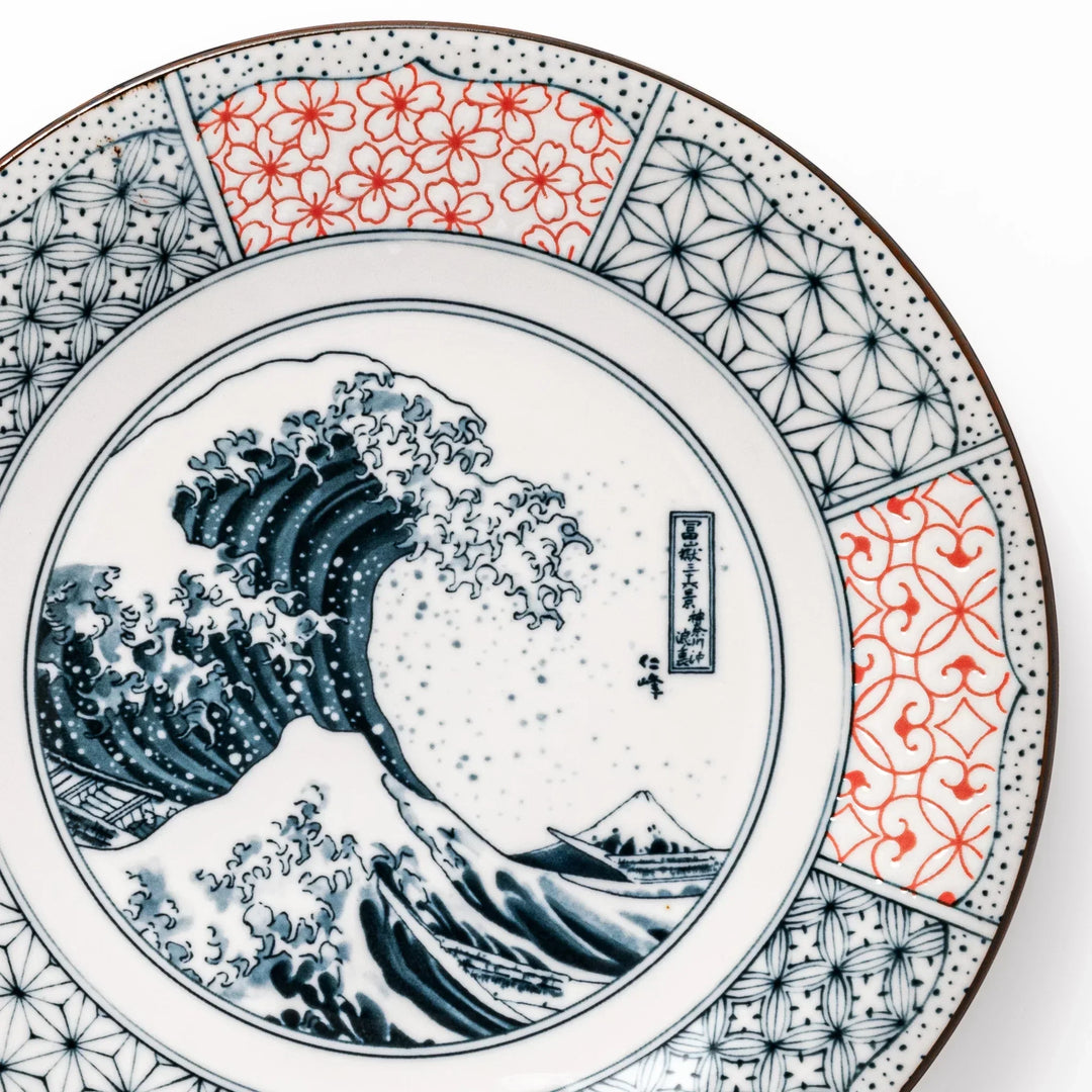 Japanese porcelain dinner plate featuring Hokusai Great Wave design with red and blue geometric border patterns.