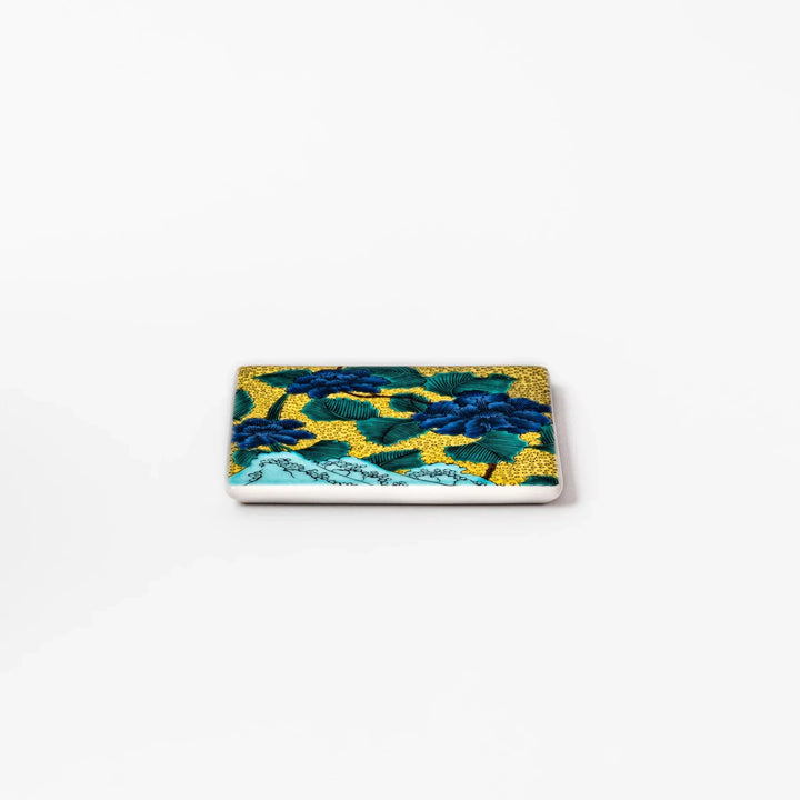 Japanese porcelain coaster with blue peony and green leaf design on yellow background, inspired by traditional Kutani ware.
