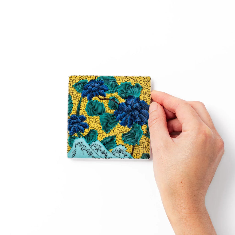 Japanese porcelain coaster with blue peony and green leaf design on yellow background, inspired by traditional Kutani ware.