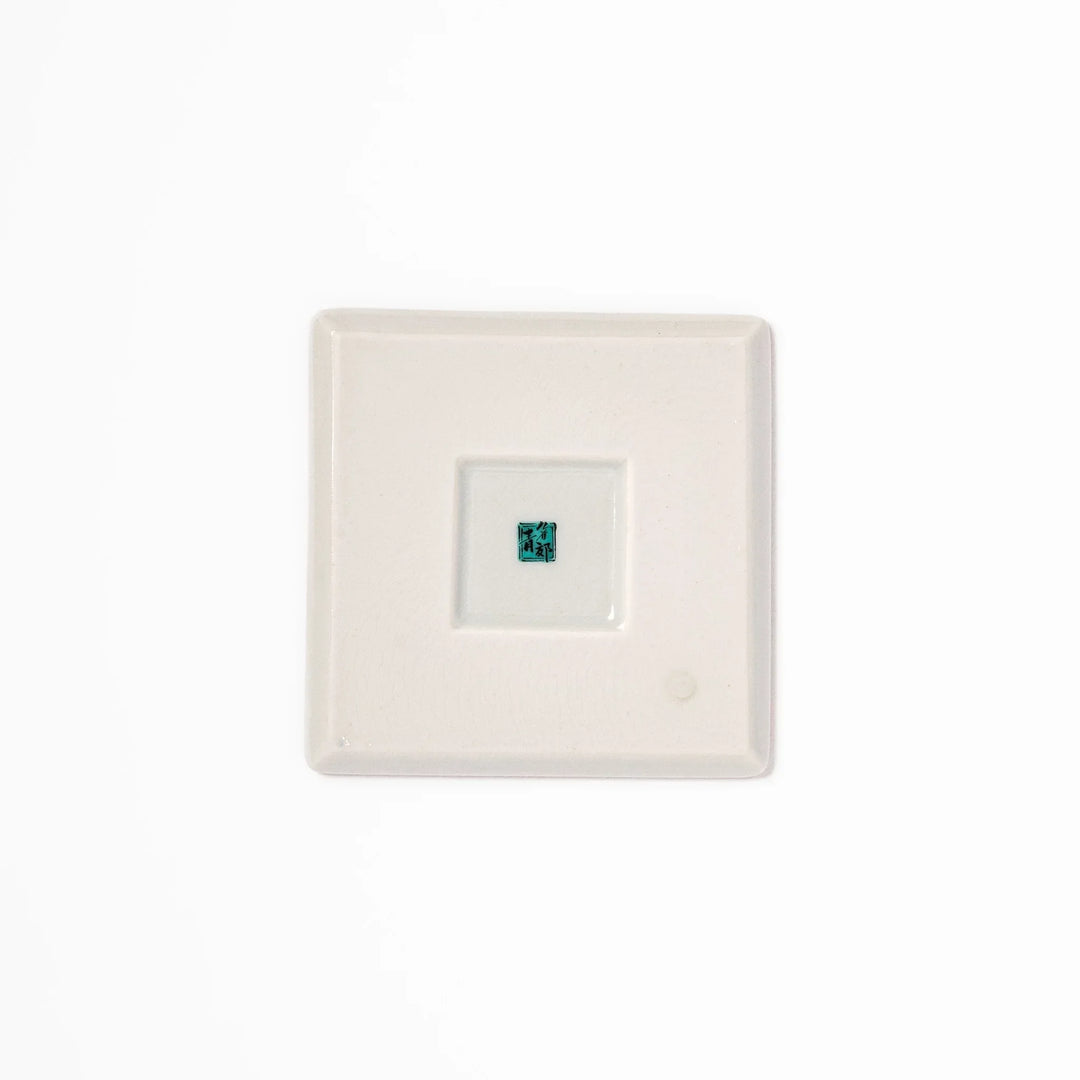 Japanese porcelain coaster with blue peony and green leaf design on yellow background, inspired by traditional Kutani ware.