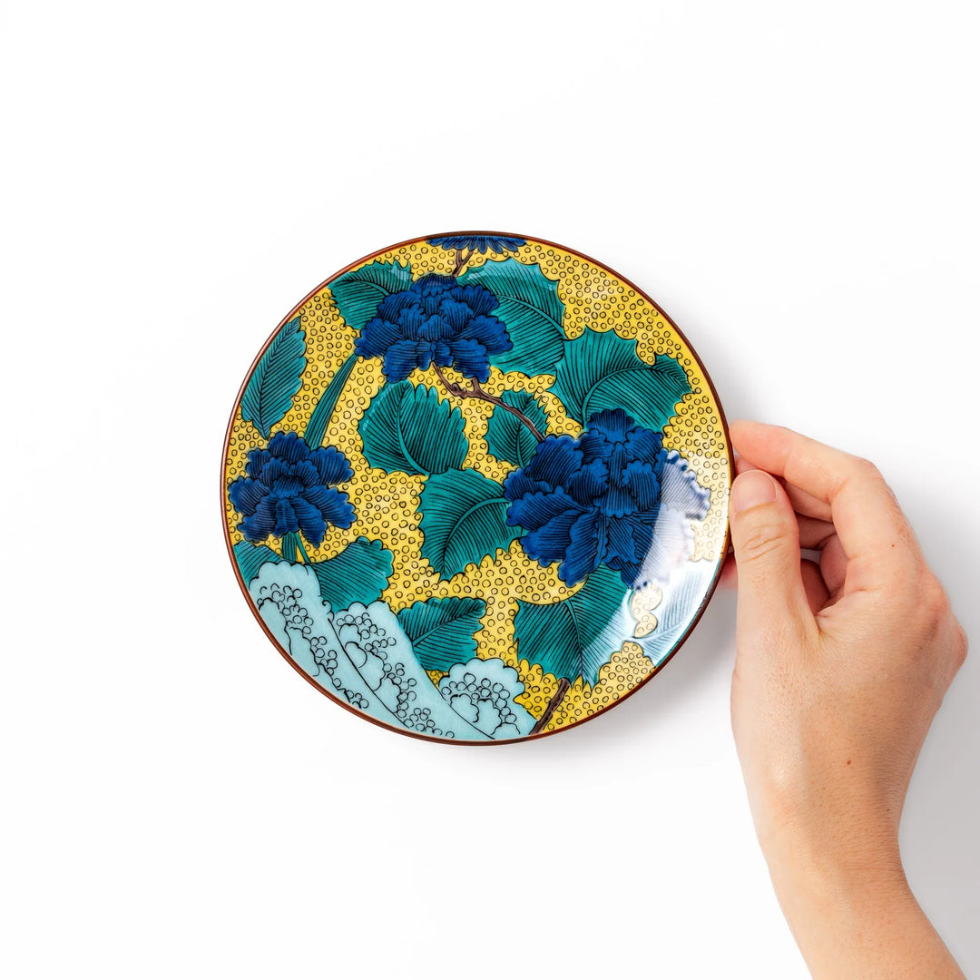Japanese porcelain dessert plate with blue peony flowers green leaves and golden yellow background.