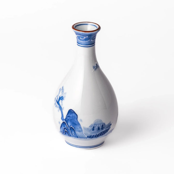 Porcelain sake flask with hand painted blue mountain and village scene red rim and elegant traditional shape.