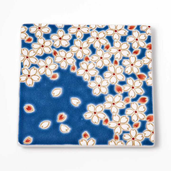 Square blue Japanese ceramic coaster with white sakura blossom and petal design for traditional dining.
