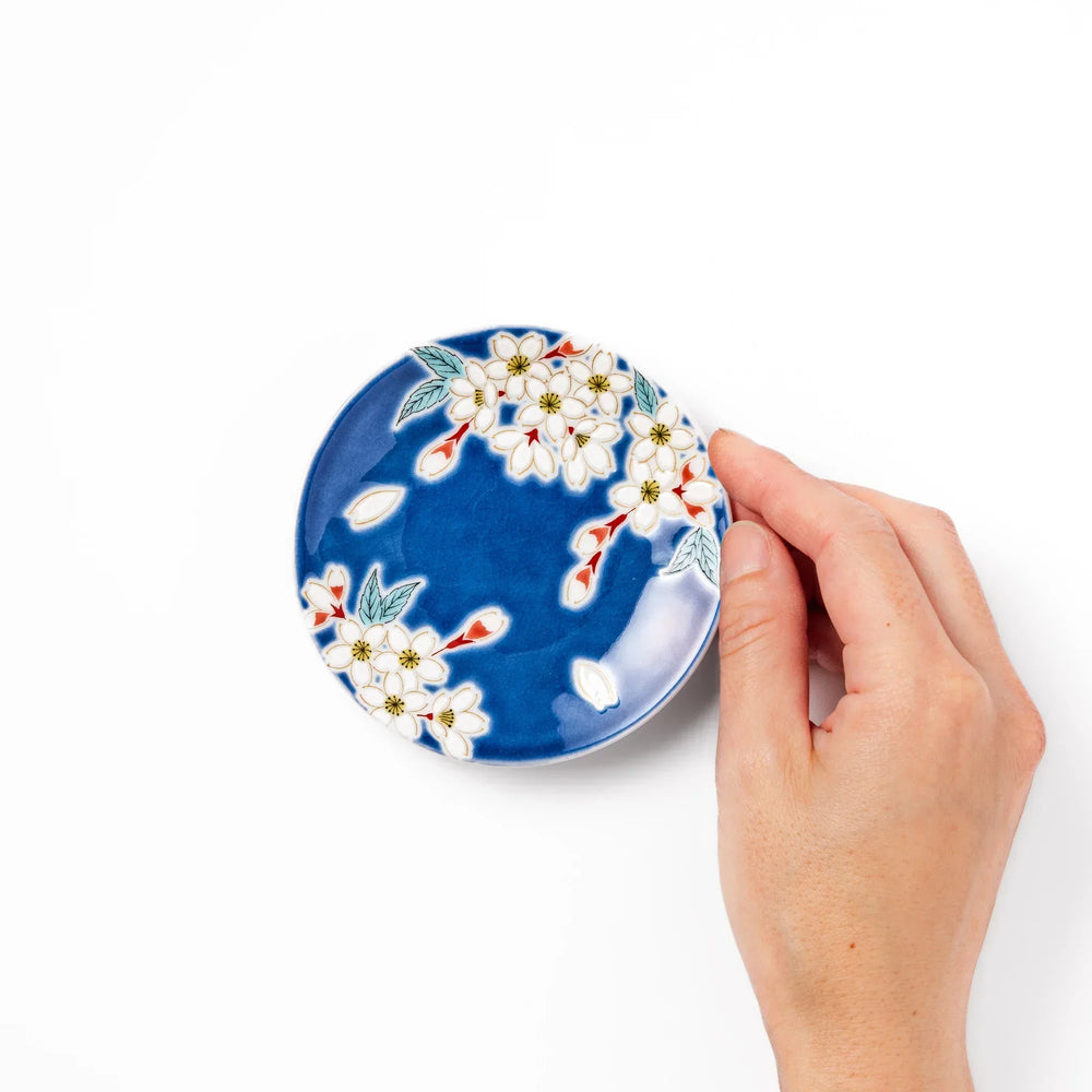 Blue Japanese ceramic sauce dish with white sakura blossom design for serving soy sauce or condiments.