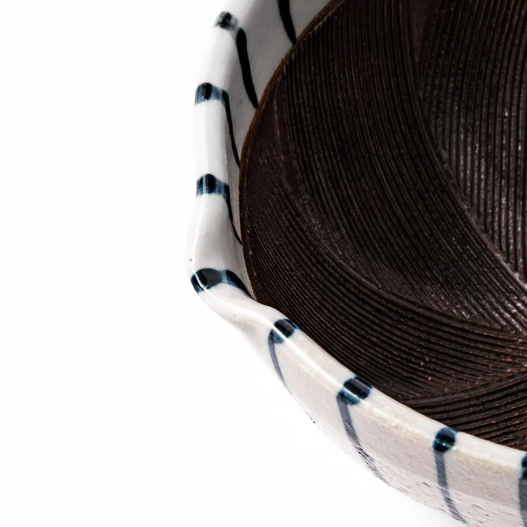 White ceramic suribachi mortar with blue stripes and brown textured interior for grinding sesame seeds.