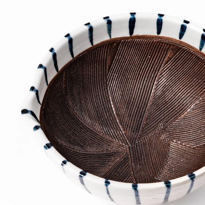 White ceramic suribachi mortar with blue stripes and brown textured interior for grinding sesame seeds.