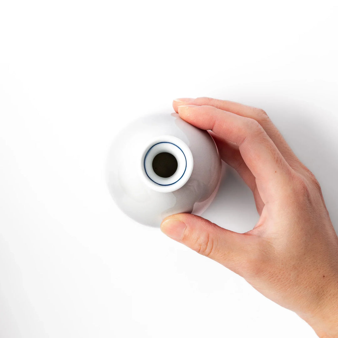 Porcelain sake flask with a smooth white body accented by traditional blue seigaiha wave patterns around the neck and base.