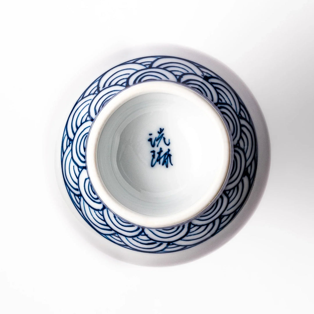 Porcelain sake flask with a smooth white body accented by traditional blue seigaiha wave patterns around the neck and base.