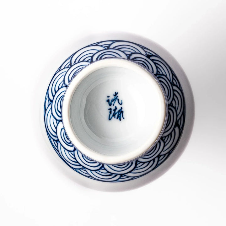 Porcelain sake flask with a smooth white body accented by traditional blue seigaiha wave patterns around the neck and base.