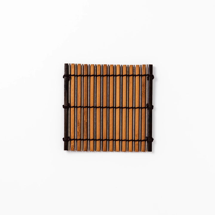 Brown bamboo coaster with alternating dark and natural slats bound with black cord for rustic table style.