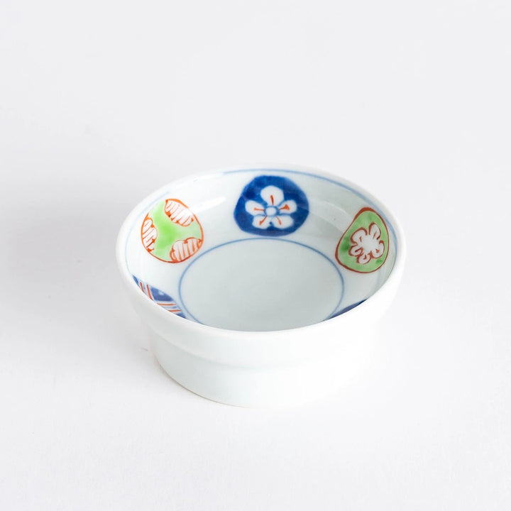 Small raised Japanese sauce dish with traditional floral and geometric motifs in red blue and green.