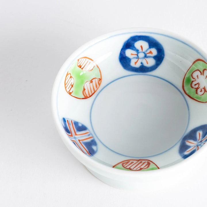 Small raised Japanese sauce dish with traditional floral and geometric motifs in red blue and green.