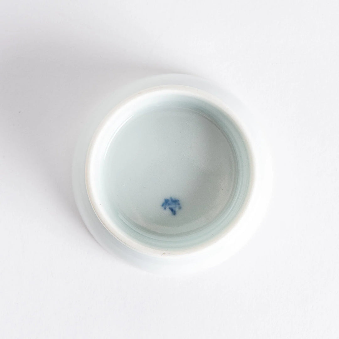 Small raised Japanese sauce dish with traditional floral and geometric motifs in red blue and green.