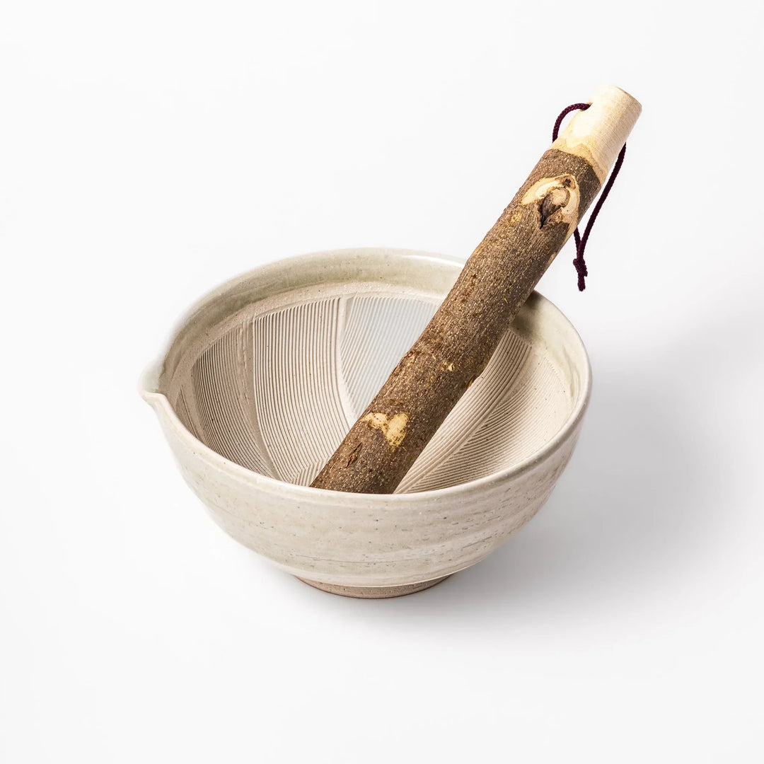 Celadon Japanese suribachi mortar with grooved interior and wooden pestle for sesame and traditional spices.