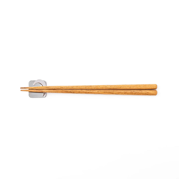 Wooden chopsticks resting on a celestial silver crescent moon chopstick holder minimalist Japanese table setting hashioki