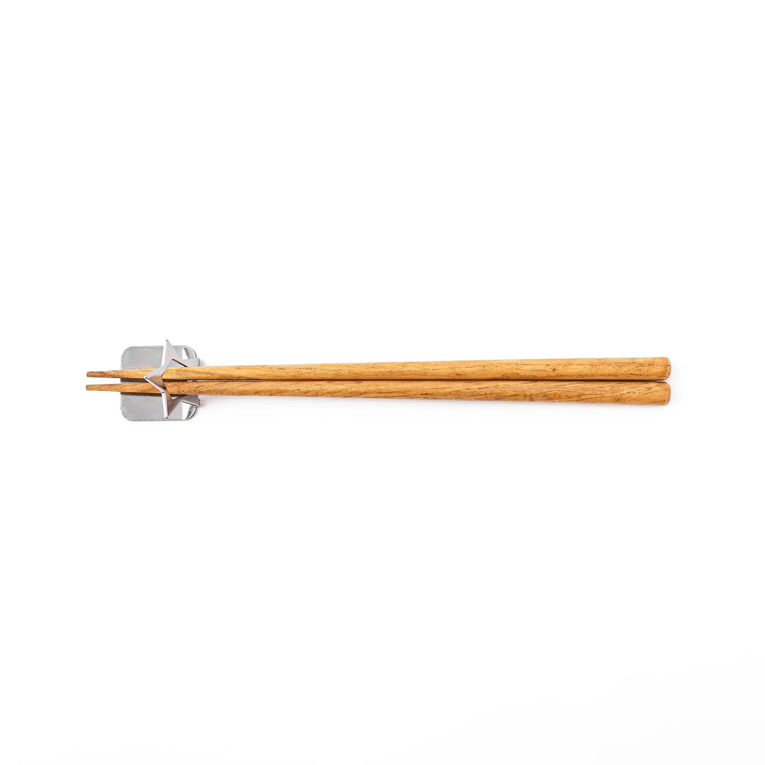 Wooden chopsticks resting on a celestial silver star chopstick holder minimalist Japanese table setting hashioki