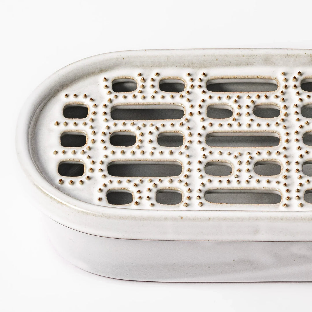 White Japanese ceramic daikon oroshi grater with built in dish and wide holes for grating daikon or ginger.