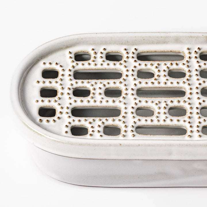 White Japanese ceramic daikon oroshi grater with built in dish and wide holes for grating daikon or ginger.