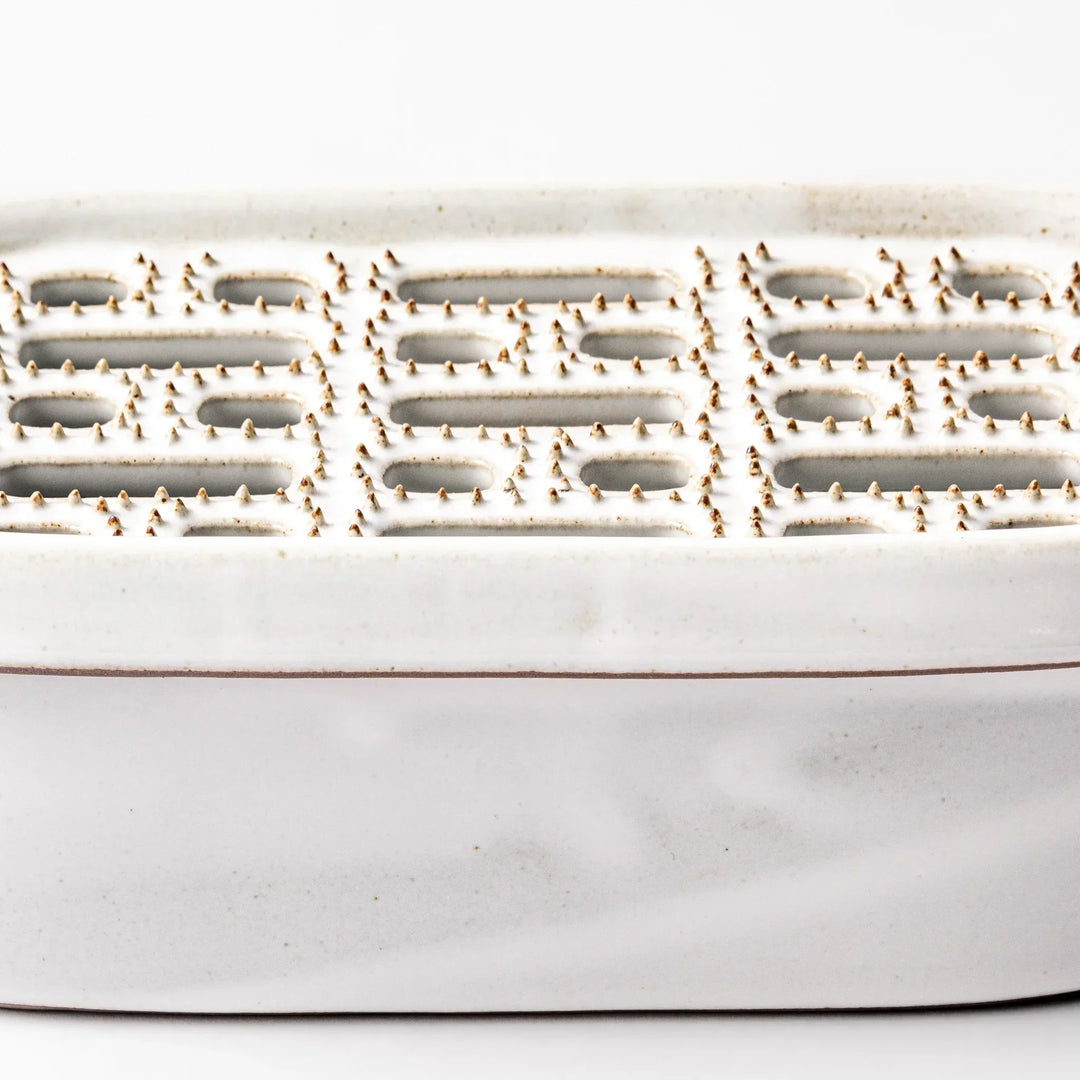 White Japanese ceramic daikon oroshi grater with built in dish and wide holes for grating daikon or ginger.