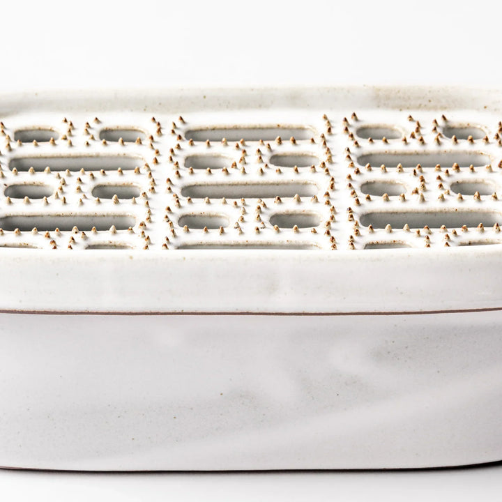 White Japanese ceramic daikon oroshi grater with built in dish and wide holes for grating daikon or ginger.