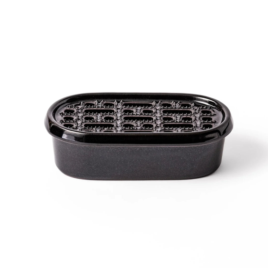 Black Japanese ceramic daikon oroshi grater with built in dish and wide holes for smooth grating cleanup.