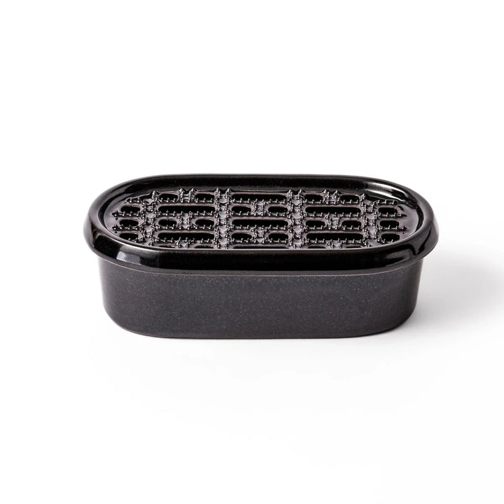 Black Japanese ceramic daikon oroshi grater with built in dish and wide holes for smooth grating cleanup.
