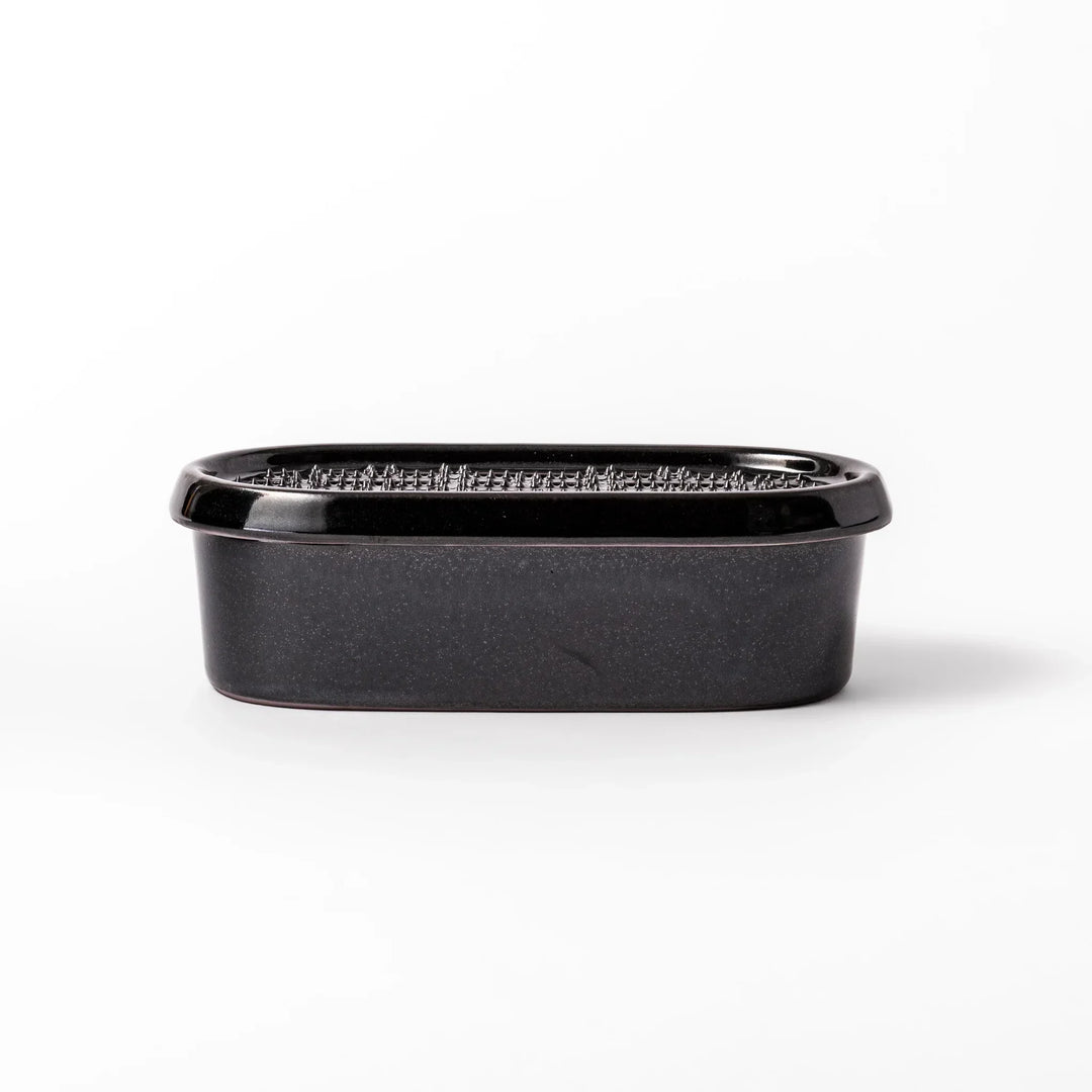 Black Japanese ceramic daikon oroshi grater with built in dish and wide holes for smooth grating cleanup.