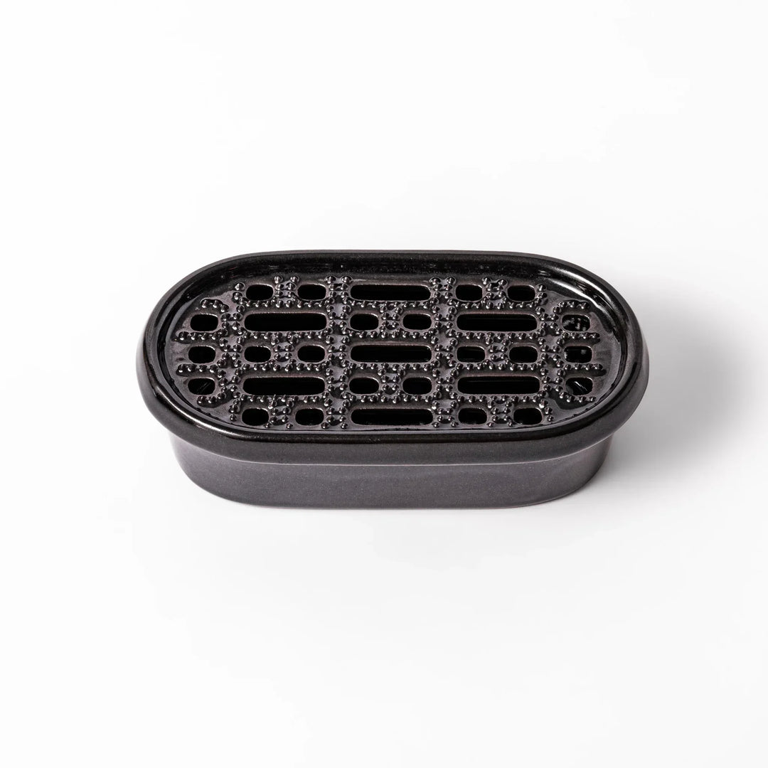 Black Japanese ceramic daikon oroshi grater with built in dish and wide holes for smooth grating cleanup.