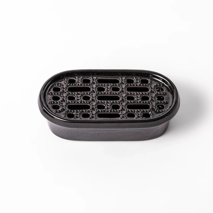 Black Japanese ceramic daikon oroshi grater with built in dish and wide holes for smooth grating cleanup.