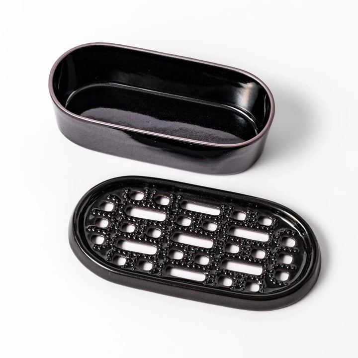 Black Japanese ceramic daikon oroshi grater with built in dish and wide holes for smooth grating cleanup.