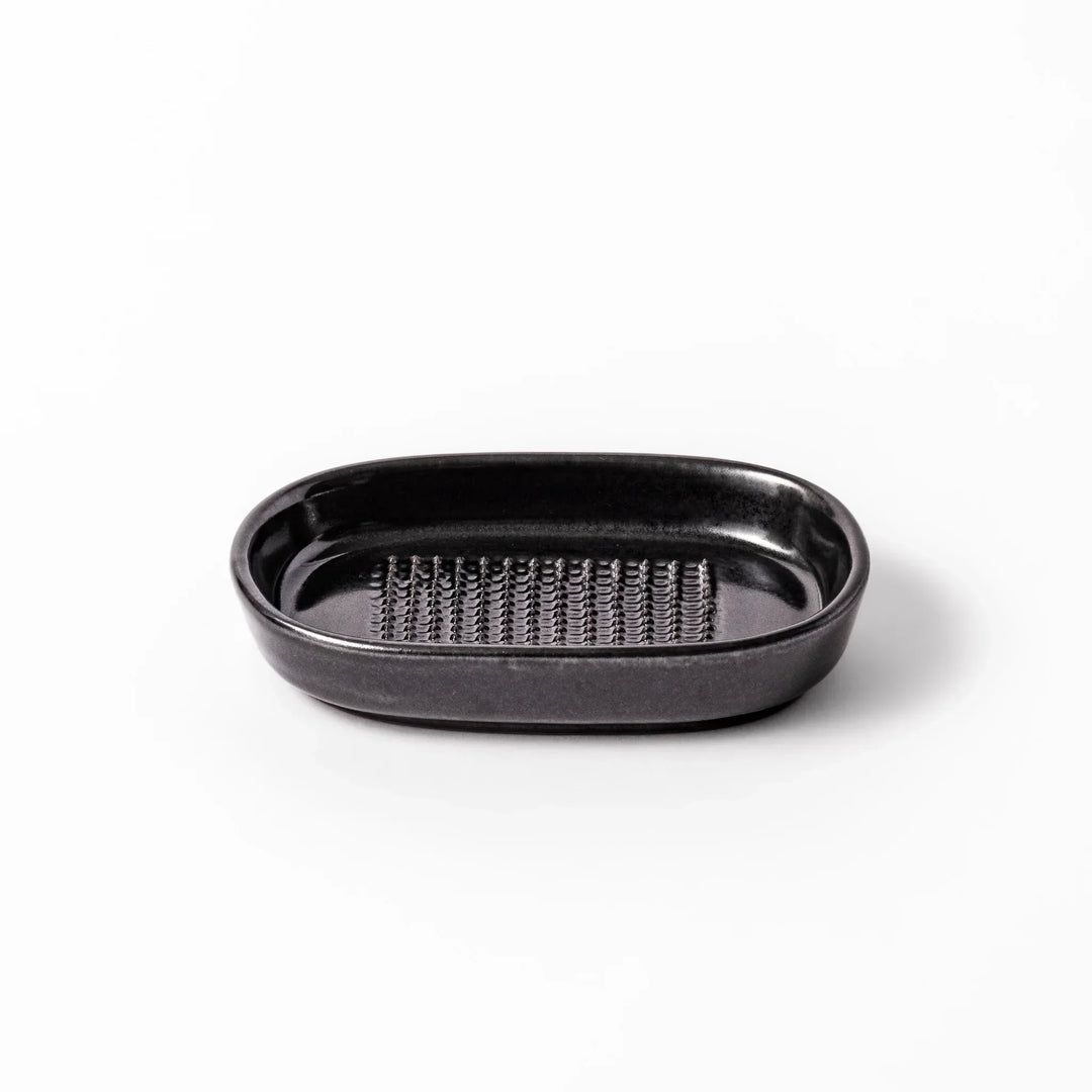 Black ceramic grater dish with raised teeth and shallow oval base, perfect for finely grating ginger, garlic, or daikon.