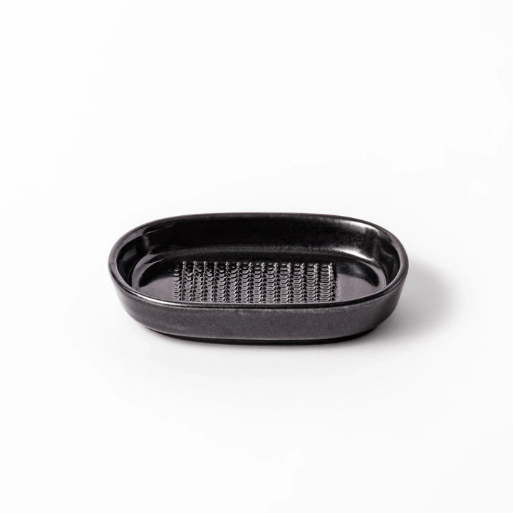 Black ceramic grater dish with raised teeth and shallow oval base, perfect for finely grating ginger, garlic, or daikon.