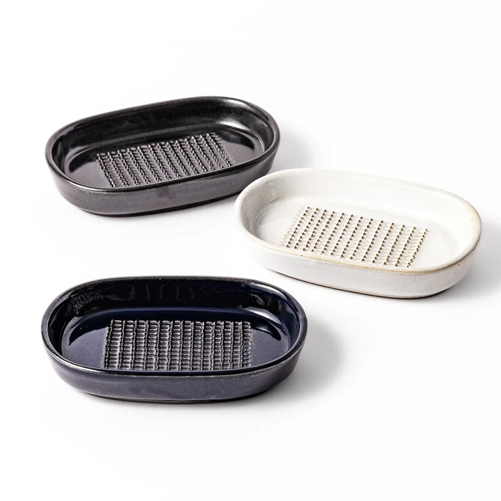 Set of three Japanese ceramic ginger grater dishes in black white and blue with raised teeth for grating.