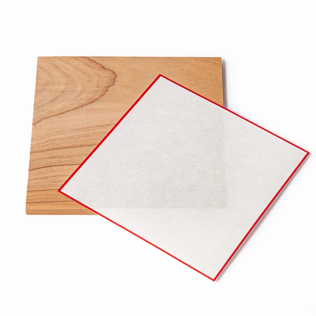 Ceramic kagami mochi jar with orange ornament on top, white two-tier design, and wooden tray for New Year decoration