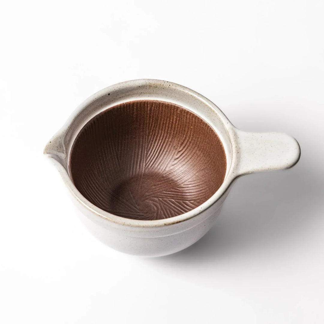 White Japanese ceramic natto suribachi bowl with brown textured interior and side handle for mixing or grinding.