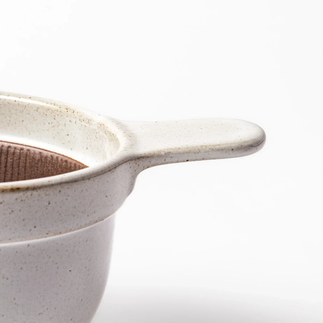 White Japanese ceramic natto suribachi bowl with brown textured interior and side handle for mixing or grinding.