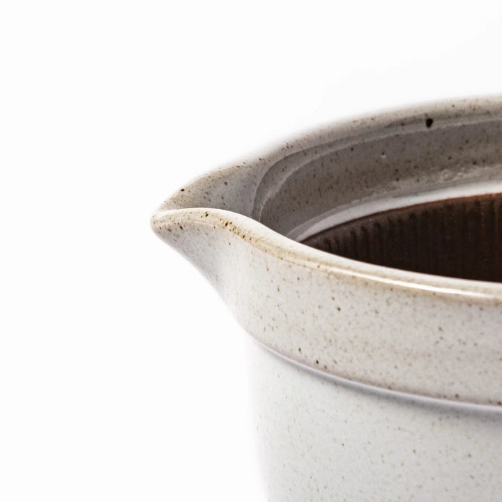 White Japanese ceramic natto suribachi bowl with brown textured interior and side handle for mixing or grinding.
