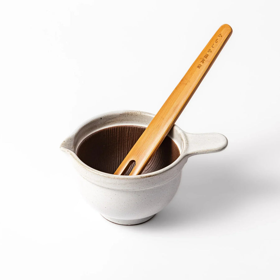 White Japanese ceramic natto suribachi bowl with brown textured interior and side handle for mixing or grinding.