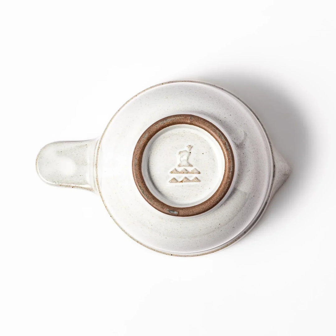 White Japanese ceramic natto suribachi bowl with brown textured interior and side handle for mixing or grinding.