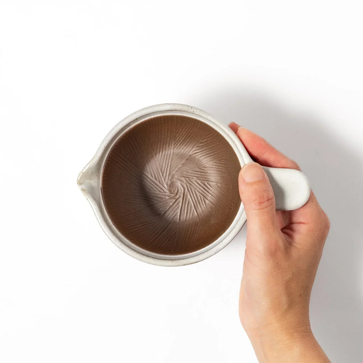 White Japanese ceramic natto suribachi bowl with brown textured interior and side handle for mixing or grinding.