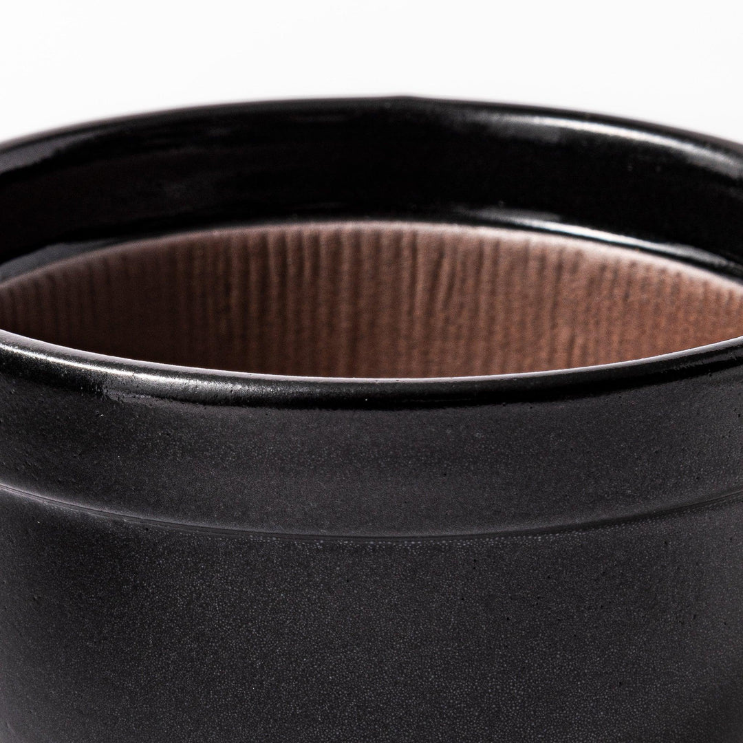 Black Japanese ceramic natto suribachi bowl with ridged brown interior and handle for mixing or grinding.