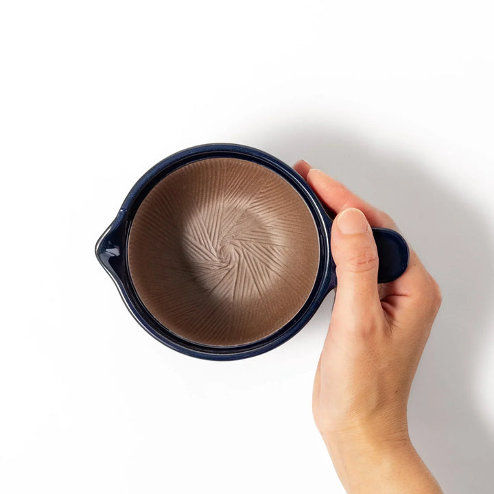 Deep blue Japanese ceramic natto suribachi bowl with ridged brown interior and handle for mixing or grinding.