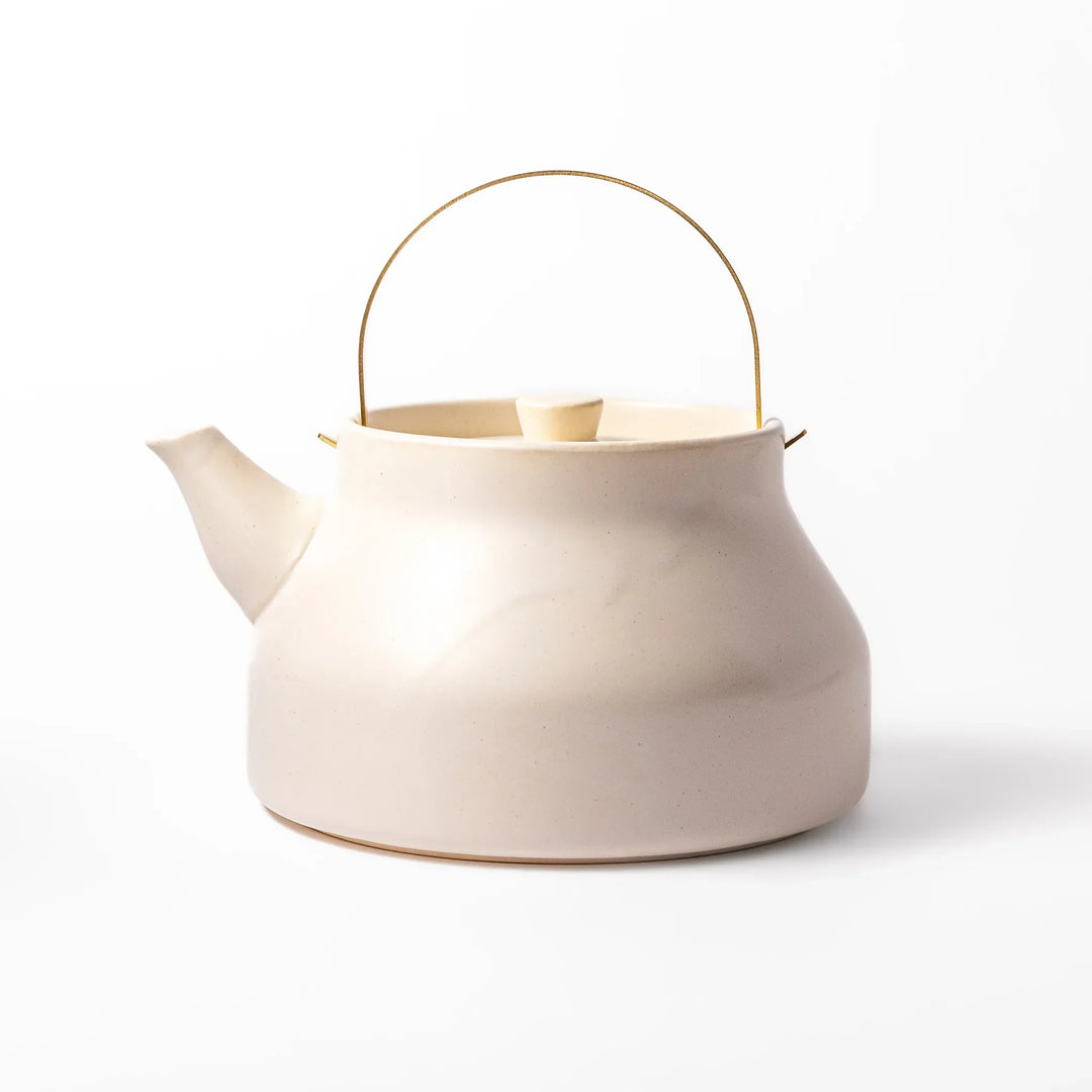 White Japanese ceramic stovetop kettle with matte finish and brass handle for daily tea brewing elegance.