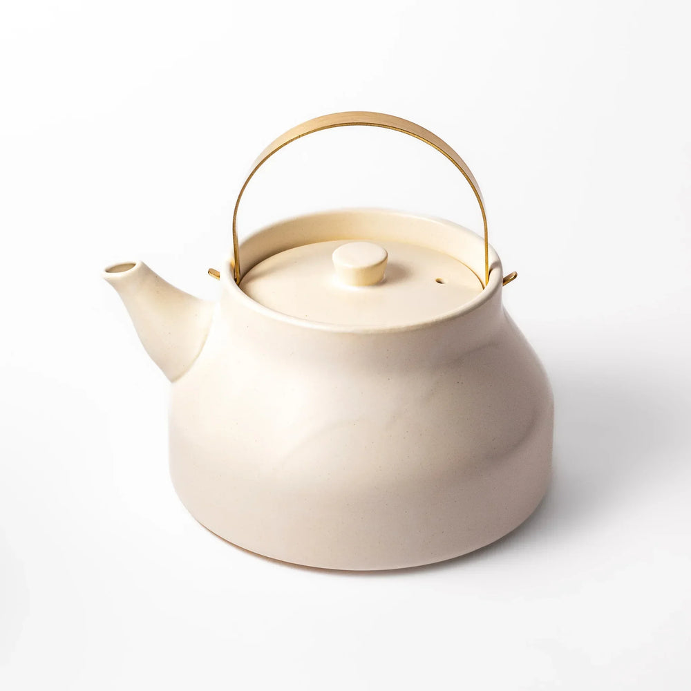White Japanese ceramic stovetop kettle with matte finish and brass handle for daily tea brewing elegance.