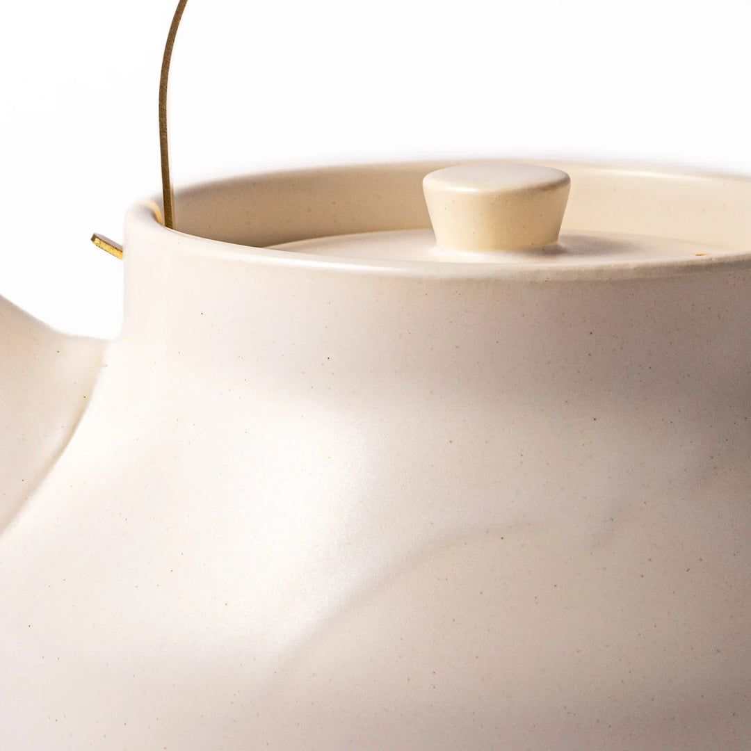 White Japanese ceramic stovetop kettle with matte finish and brass handle for daily tea brewing elegance.