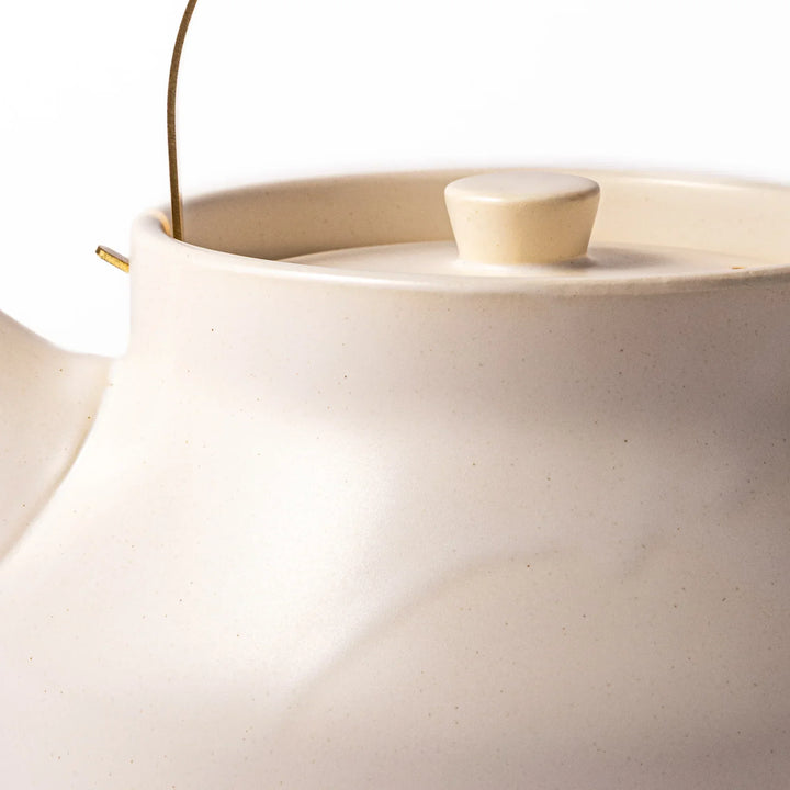 White Japanese ceramic stovetop kettle with matte finish and brass handle for daily tea brewing elegance.