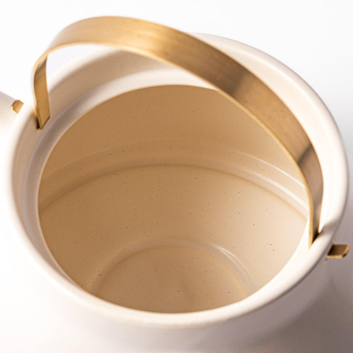White Japanese ceramic stovetop kettle with matte finish and brass handle for daily tea brewing elegance.