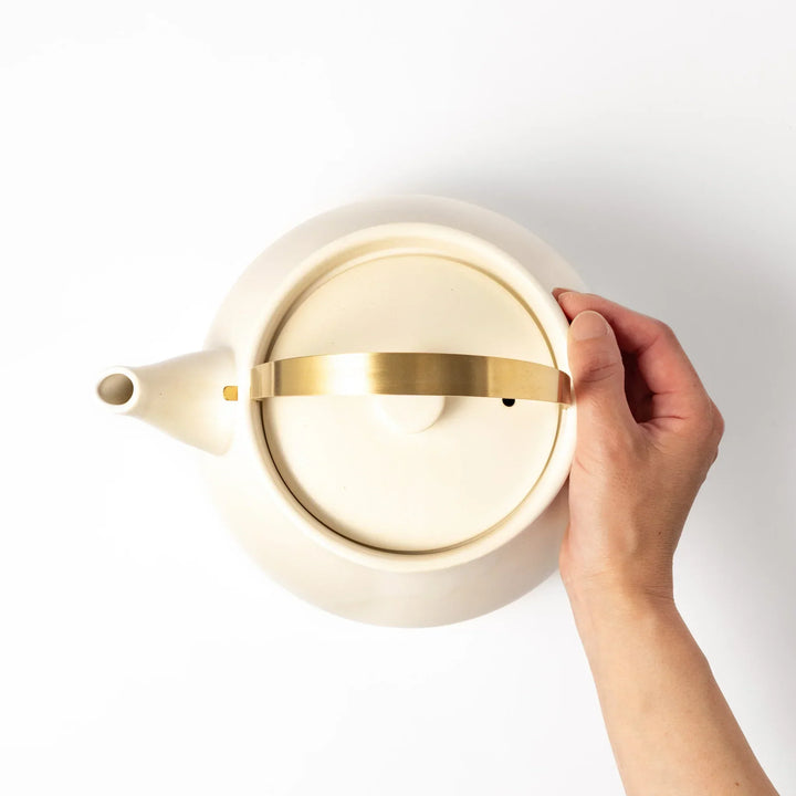 White Japanese ceramic stovetop kettle with matte finish and brass handle for daily tea brewing elegance.
